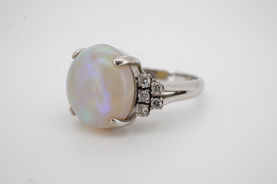 A 9k white metal and single stone cabochon white opal set dress ring, with ten stone diamond set shoulders, size P, gross weight 6.5 grams. Condition - poor